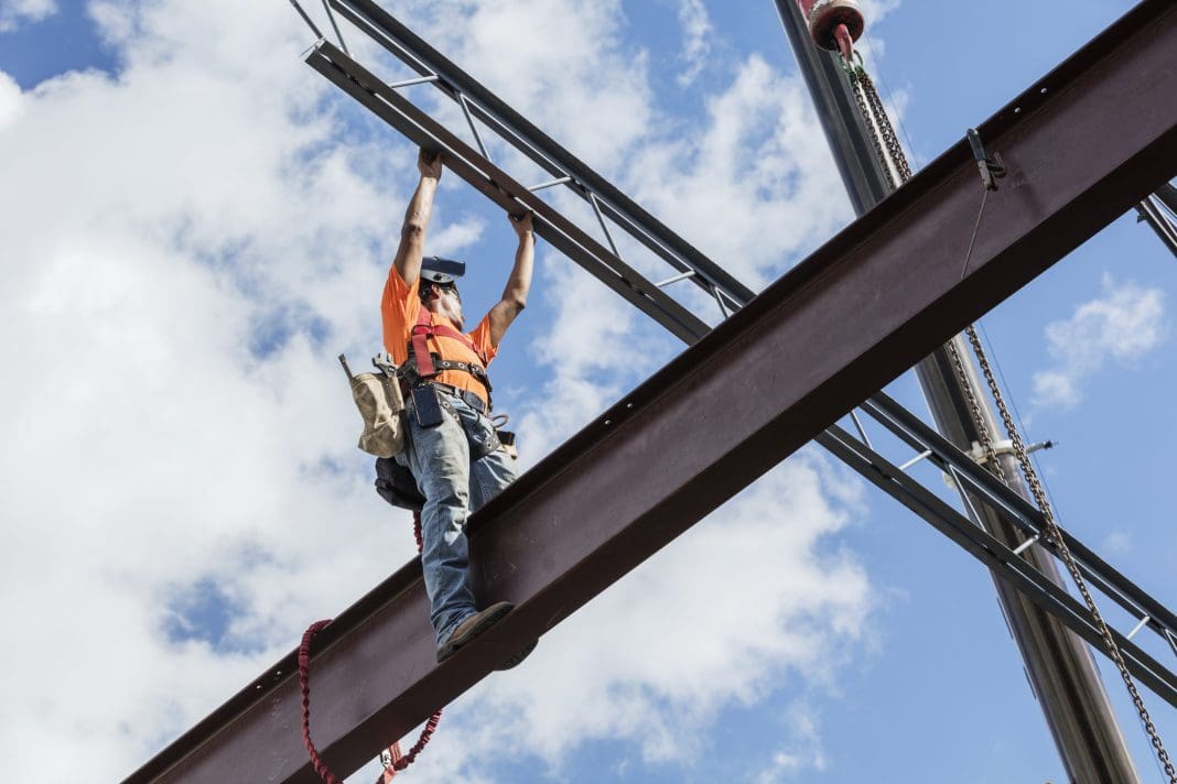 Ironworker at construction site installing roof joist A worker erecting a steel frame construction, the kind Intrastack encourages offsite construction of