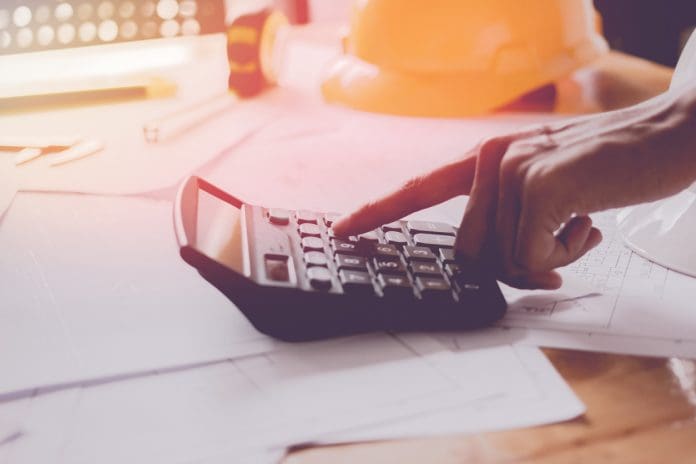 Close up man hand using calculator Calculating bonus(Or other compensation) to employees to increase productivity.Writing paper on desk.Selective Focus