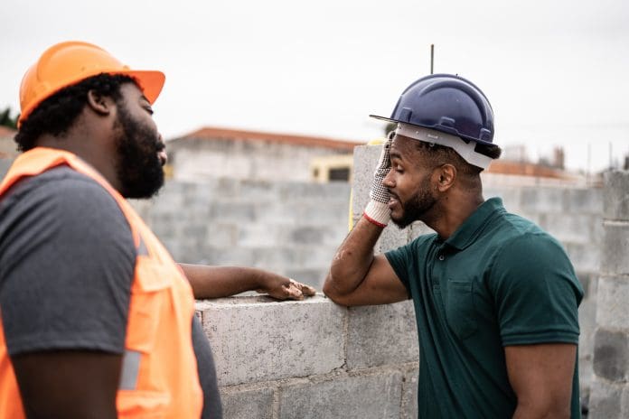 Worried coworkers talking in a construction site Worried coworkers talking in a construction site