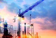 UK construction industry witnesses 16.5% increase in new orders tower cranes at construction site with sunset