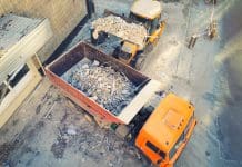 Getting to grips with waste management in the construction industry Bulldozer loader uploading waste and debris into dump truck at construction site. building dismantling and construction waste disposal service. Aerial drone industrial background