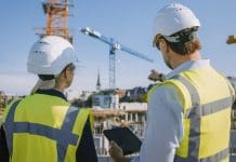 On-demand webinar: Navigating the Building Safety Act Male Civil Engineer and Young Female Building Architect Use a Tablet Computer on a City Construction Site. They Talk About the Future of Real Estate Development and Planning. Wearing Safety Hard Hats.