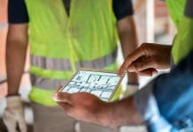 New year, new systems. Embracing change in building control in 2025 Close-up of a male architect using a digital tablet for discussing construction plan with colleagues at a construction site. Construction site engineer reviewing blueprints on digital tablet, representing building control in 2025