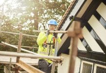 Advantage’s Views On Third Party Certification a young male roofer carrying scaffold pole on the roof, representing need for third party certification in the construction sector
