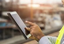 D2 and Sterling DCS partner to advance sustainable programme management in infrastructure projects Engineer man or architect use tablet with white safety helmet in city construction site . Standing on rooftop building construction at capital.