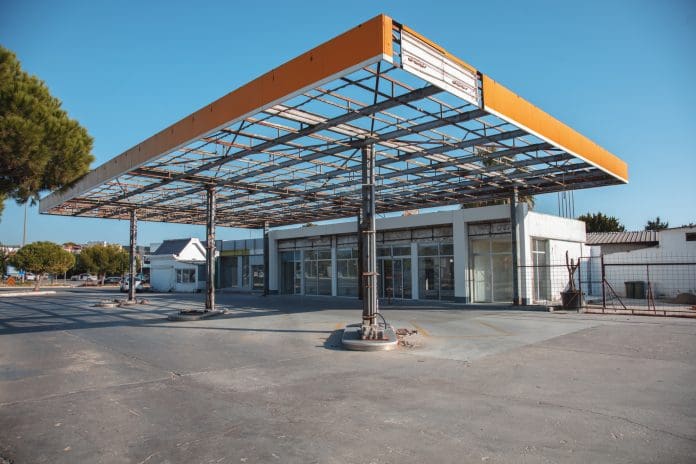 A disused petrol station with a decaying canopy representing grey belt land