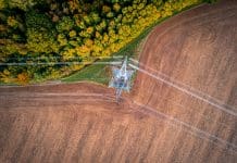“Seismic reforms” promised in new Planning and Infrastructure Bill 400kV extra high voltage electricity line changing direction above cultivated field contracting with autumn forest, shot from above with drone, representing the new planning and infrastructure bill
