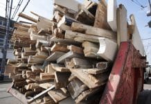 The benefits of using recycled materials in civil engineering Rust red skip loaded with a pile of old wood from home for recycling