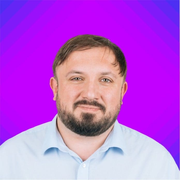 Headshot of Andrew Alsbury of AtkinsRealise facing the camera against a purple backdrop