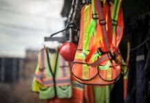 Navigating the new era of Building Control: Key takeaways from our CPD webinar Picture of PPE, or personal protective devices, for sale in a shop, haning. Yellow and Orange vests, harnesses and helmets are visible, representing building control webinar