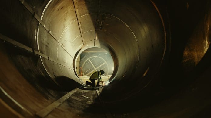 Professional Heavy Industry Worker Wearing Helmet Welding Inside Oil and Gas Pipe. Construction of the Oil, Natural Gas and Biofuels Transport Pipeline. Industrial Manufacturing Factory, representing hinkley point c strike