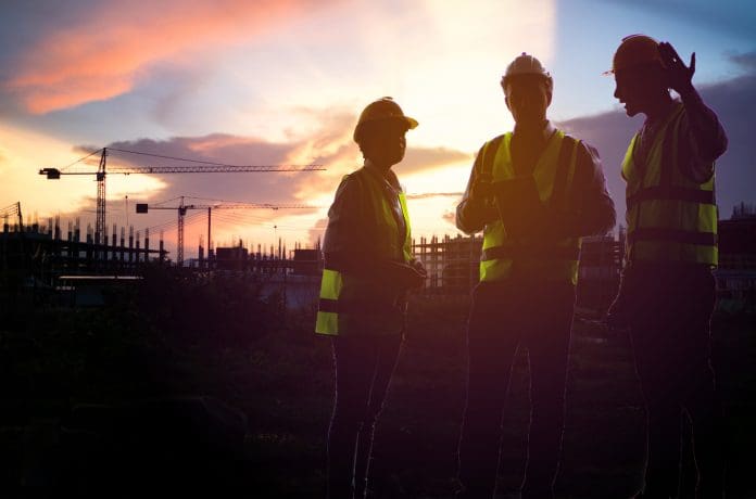 Teamwork, worker in uniform and wearing safety helmet while working on commercial dock site with container box from cargo freight ship for import export. Teamwork, worker in uniform and wearing safety helmet while working on commercial dock site with container box from cargo freight ship for import export, representing structural warranty