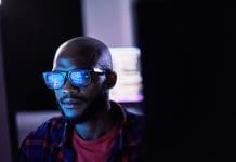 Most engineering firms in UK anticipate digital transformation will help drive ambitious profit and headcount goals Cyber security, black man and code reflection in eyewear, hacking and software update in office. African American male employee, programmer or IT specialist with glasses, focus and cloud computing, representing digital technology