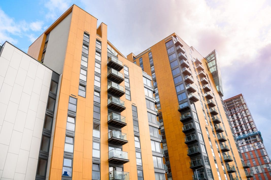 Modern high rise blocks of flats in a city centre under partly cloudy sky in summer. A building under construction is visible in distance. Manchester, England, UK, representing BTR