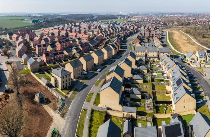 Aerial panorama landscape view of a large new build housing development on green belt land due to a housing shortage with characterless design for first time buyers, representing planning reform