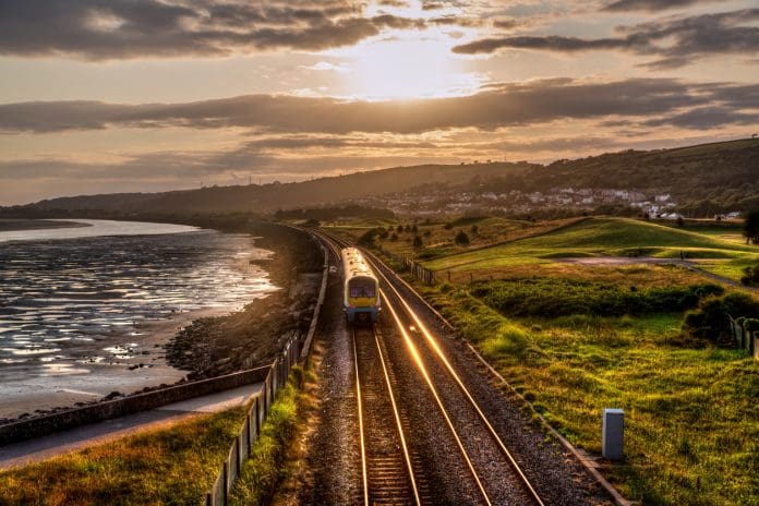Train travelling past sea wall at sunset, representing infrastructure delivery reforms announced by the government