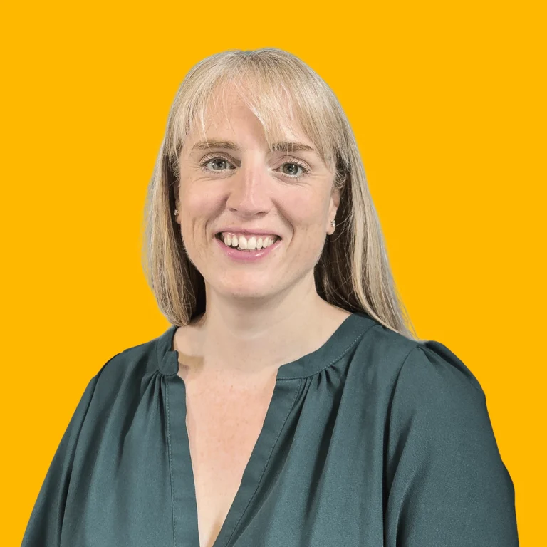 Headshot of Kirsty Cogan, managing director of SFG20, against a yellow backdrop smiling and looking towards the camera