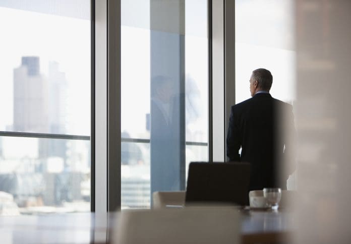 Businessman looking out conference room window, representing D&O Insurance