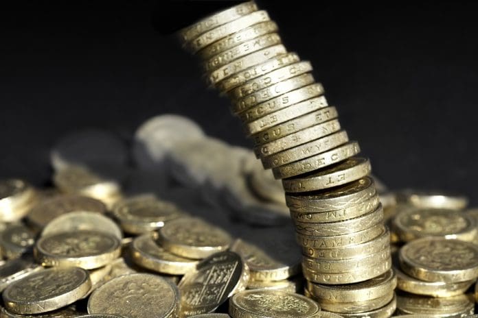 Stack of one pound coins falling over, representing the impact of National Insurance Contributions on the construction industry