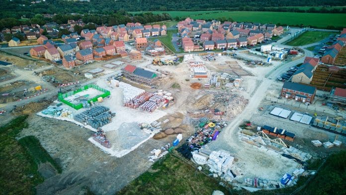 Aerial view of a residential construction site with partially completed houses and materials.