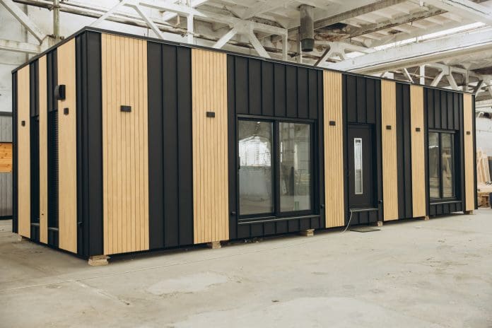 Modern prefabricated tiny house being built inside a spacious factory, showcasing innovative construction techniques