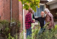 Four points to consider when undertaking work on a party wall Group of senior men of various backgrounds having a friendly chat in the front yard of one man while he is raking the leafs, representing neighbourly discussions about party wall work