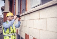 Understanding Efficacy Cover: silent vs. specific coverage in business insurance Building inspector, architect, engineer, general contractor, repairman insurance adjuster, or other blue collar worker inspecting the exterior walls of residential building. Wearing a safety vest, yellow helmet and clear safety glasses, he is checking very meticulously every deficiency and photographs them using his large screen phone, representing efficacy cover