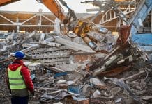 Circular Construction Hub aims to increase reuse of building materials in Scotland Powerful excavator destroyer removes debris under professional worker control at demolish site under blue sky on winter day, representing a circular economy