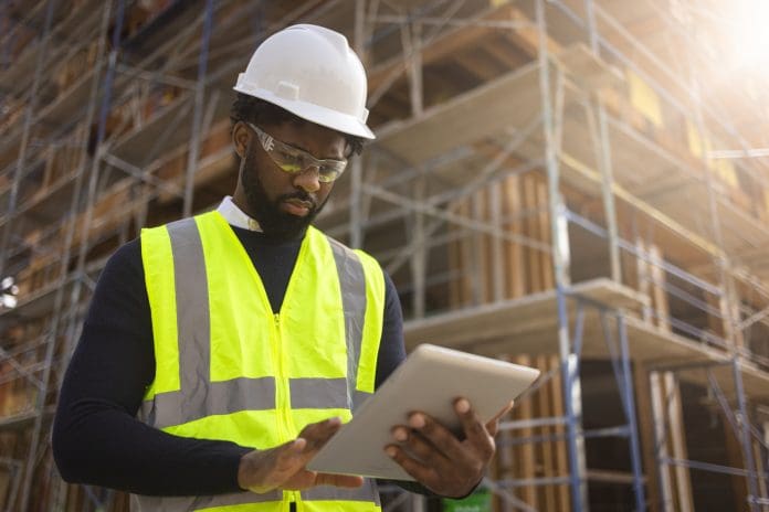 A young black man is a project manager at a residential construction site.