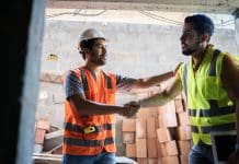 CIC signs Conflict Avoidance Pledge to encourage collaborative working in the built environment Construction workers shaking hands at a construction site, representing the kind of collaborative working the conflict resolution pledge aims to encourage