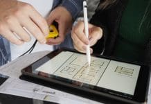 Made to measure: Why construction data should fit like a bespoke suit Close-up of two architects making notes on drawing on digital tablet with blue print at office
