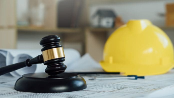 Labor and Construction law concept.judge gavel with yellow safety hat,blueprint,home model backgound.Government service protecting safety at job. Worker security protection policy, all representing the Laing O'Rourke - BDP case.