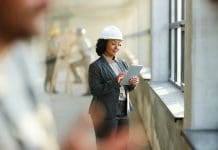 From bids to builds: How construction ERP platforms helps win and deliver projects Smiling female building contractor working on touchpad at rebuilding site, representing construction ERP platforms