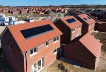 Net-zero or no-go: why sustainable building codes are shaping the future of UK housing The roofs of a row of new build houses on a construction site with roof integrated or In-Roof solar panels for cheap and sustainable energy in an eco friendly property, representing sustainable building codes