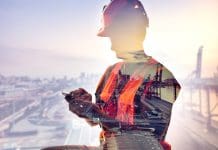 NBS and GS1 construction product data partnership to boost digital transformation Cargo dock male worker using mobile phone against cargo dock double exposure