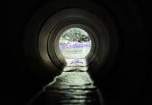 Making water discharge an early priority crucial for well-regulated, compliant sites View through a round concrete tunnel carrying a water discharge beneath a road