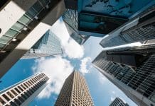 UK professional services firms fast-track digital transformation by two years with Deltek Cloud ERP Skyscraper, cloud on sunny sky, corporate business building in Hong Kong central financial district. Low angle view. Enterprise organisation company, Asia economy, office people job work concept, representing Deltek's ERP solutions