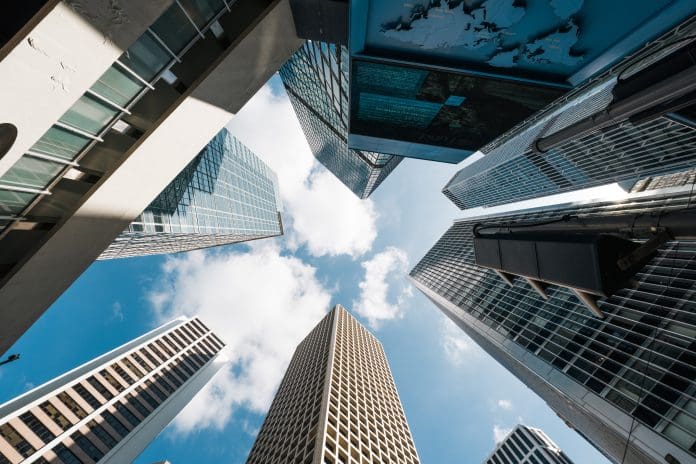 Skyscraper, cloud on sunny sky, corporate business building in Hong Kong central financial district. Low angle view. Enterprise organisation company, Asia economy, office people job work concept, representing Deltek's ERP solutions