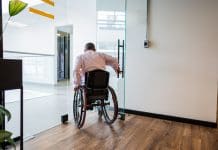 Dismantling DE&I is damaging to communities, businesses and profits Rear view of a wheelchair businessman leaving room on the office
