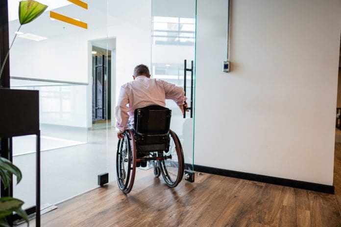 Rear view of a wheelchair businessman leaving room on the office