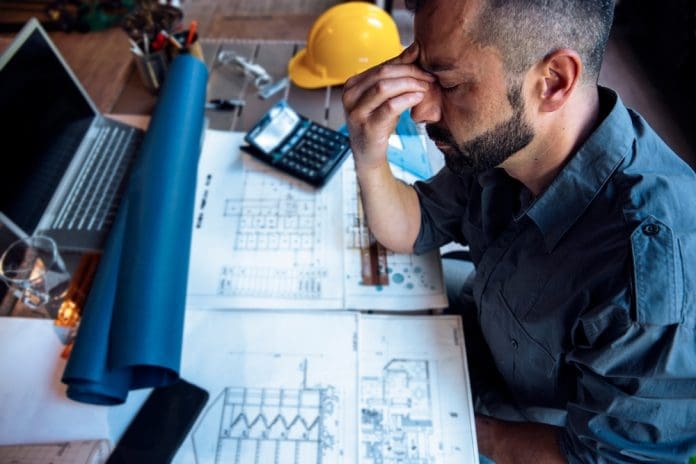 Overworked,Stressed,Man,Engineer,Having,Headache,While,Working,On,His, representing the importance of schedule certainty in construction