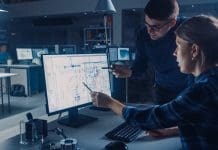 Ethical AI for efficient and effective use in construction Engineer Working on Desktop Computer, Screen Showing CAD Software with Technical Blueprints, Her Male Project Manager Explains Job Specifics. Industrial Design Engineering Facility Office