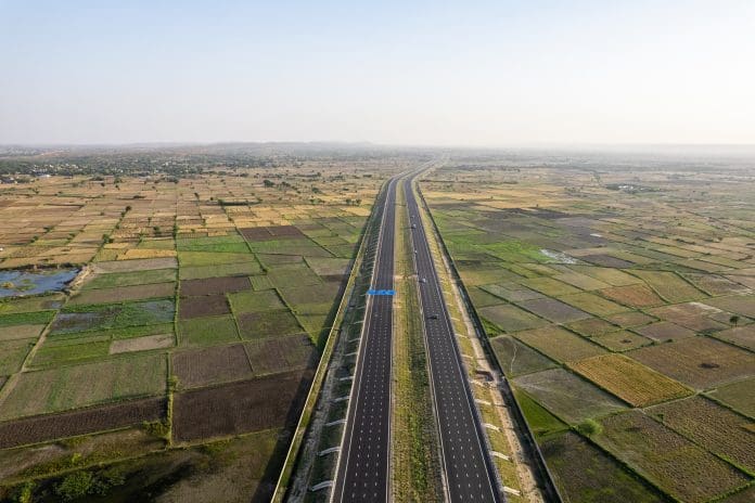 orbit aerial drone shot of new delhi mumbai jaipur express elevated highway showing six lane road with green feilds with rectangular farms orbit aerial drone shot of new delhi mumbai jaipur express elevated highway showing six lane road with green feilds with rectangular farms on the sides