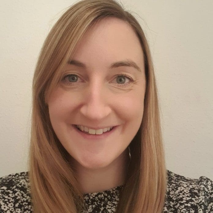 A headshot of Sophie Cox smiling against a light grey background