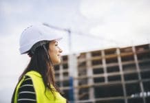 A new approach to inspiring young people in construction Side view portrait of beautiful woman architect standing in front on construction site at sunset.