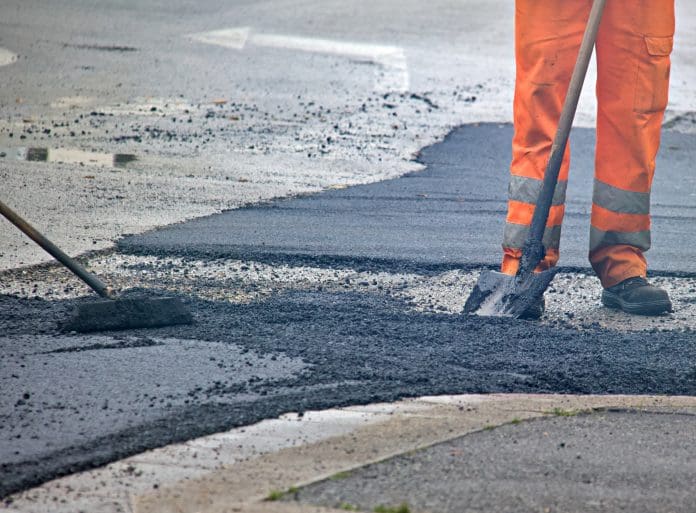 Man repairing a hole in the street construction firm fined worker fatally struck road resurfacing road sweeper