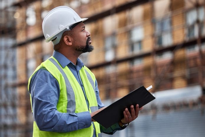 Shot of a contractor filling out paperwork at a construction site