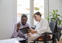 Accessibility training sessions highlight need for sharing, not shielding a businesswoman in a wheelchair with a disability looking at the digital tablet with her multiethnic business partner discussing the business plan, representing accessibility training