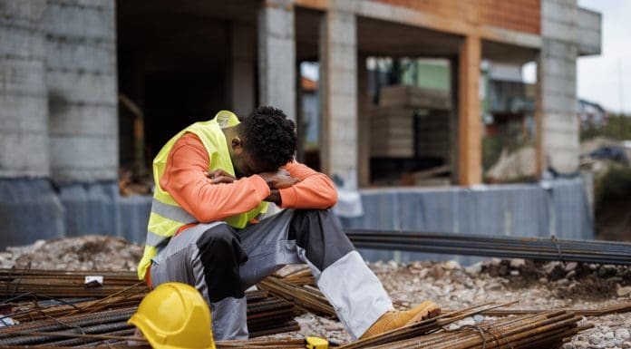 Exhausted construction worker taking a break at construction site, representing the risk of modern slavery in uk housebuilding