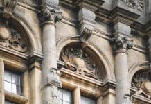 Why specialist expertise is essential to preserve the UK’s built heritage and architectural legacy Oxford, UK – 20th March 2024: The building detail and architectural features of the building located at in Oxford, Oxfordshire, England, United Kingdom, Great Britain, Europe. No people seen in the photograph. Architectural Features of Central Oxford Building Location: Central Oxford, Oxfordshire, England, United Kingdom Date of Photograph: 20th March 2024 The building exhibits a blend of Gothic and Victorian architectural styles, common in central Oxford. The façade is characterised by ornate stone carvings and pointed arches. The structure primarily uses local limestone, which lends a distinctive warm, honey-coloured appearance, typical of many historic buildings in Oxford. Large, arched windows with intricate tracery and stained glass are prominent. The windows are set within deep reveals, providing a sense of depth and shadow. The roofline is punctuated by steeply pitched gables and decorative finials, contributing to the vertical emphasis typical of Gothic architecture. The main entrance features a grand, pointed arch doorway, often adorned with detailed stonework and flanked by columns. Elaborate cornices and parapets run along the building’s edges, incorporating decorative stone motifs such as fleur-de-lis and other heraldic symbols. The building maintains a balanced and symmetrical layout, with a clear emphasis on verticality and proportion. Flying and engaged buttresses are present, providing both structural support and decorative appeal. The architectural style reflects Oxford’s historical significance and its long-standing association with academia and ecclesiastical heritage. This building exemplifies the rich architectural tapestry of central Oxford, seamlessly integrating historical elements with a timeless aesthetic.